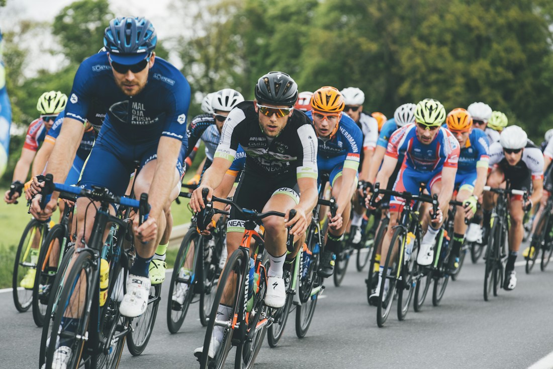 Cyclists riding together on a tree-lined road